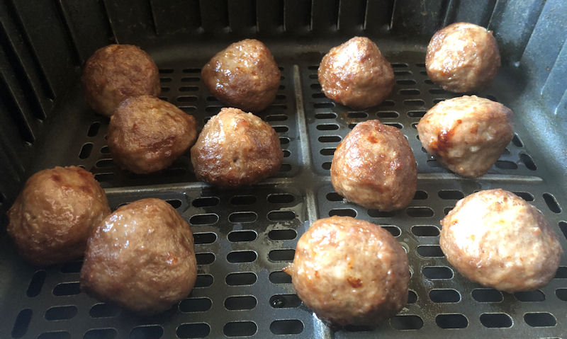 Partially cooked air fried 12 beef meatballs sat in air fryer basket