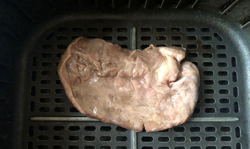 Partially cooked Sizzle Steak sat in air fryer basket