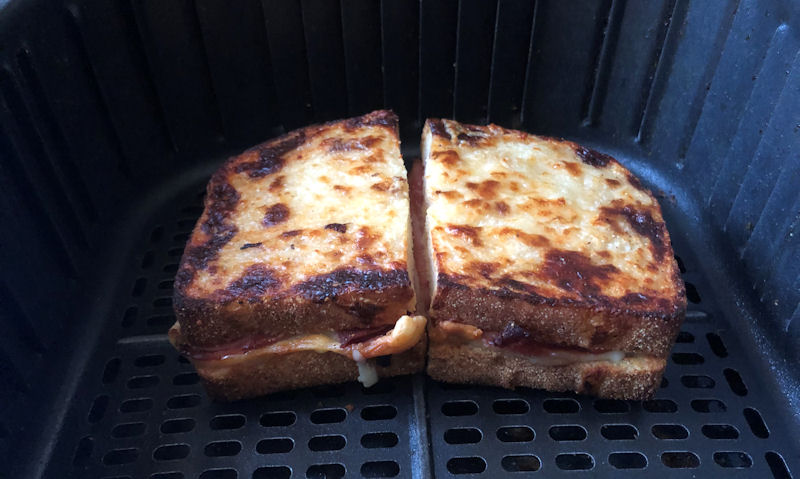 Well cooked ham, cheese toastie sitting in air fryer basket