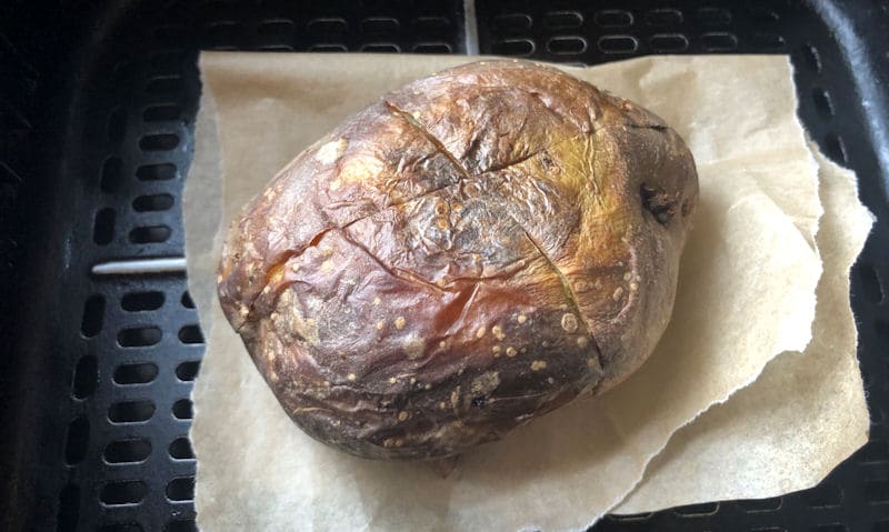 Jacket potato reheated in air fryer basket on parchment paper