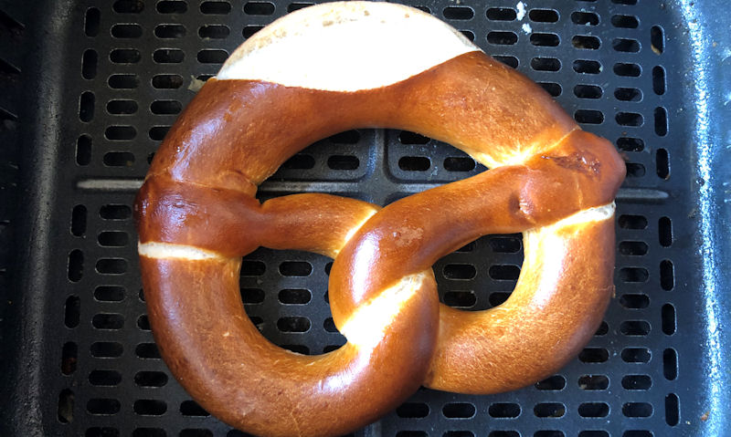 Cooked pretzel sitting in bottom of air fryer basket