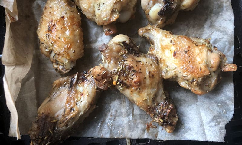 Reheated chicken wings sitting in air fryer on parchment paper