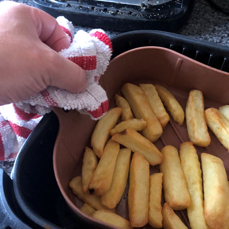 Pulling silicone basket out of air fryer with kitchen towel