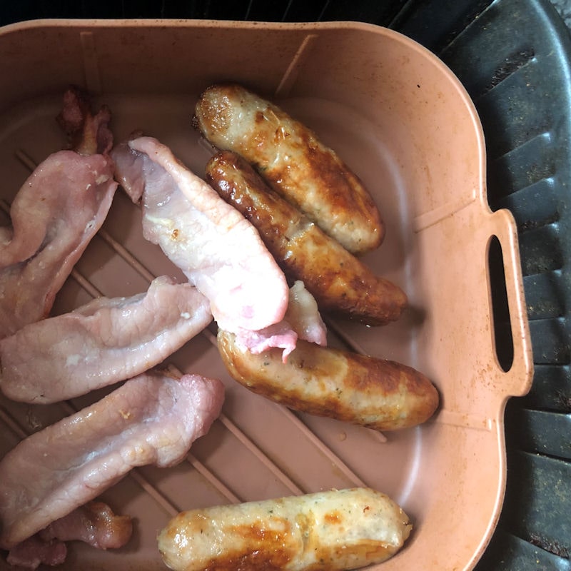 Cooked sausage and bacon rashers sitting in silicone basket