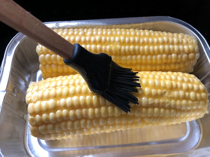 Me brushing melted butter over air fried corn on the cob