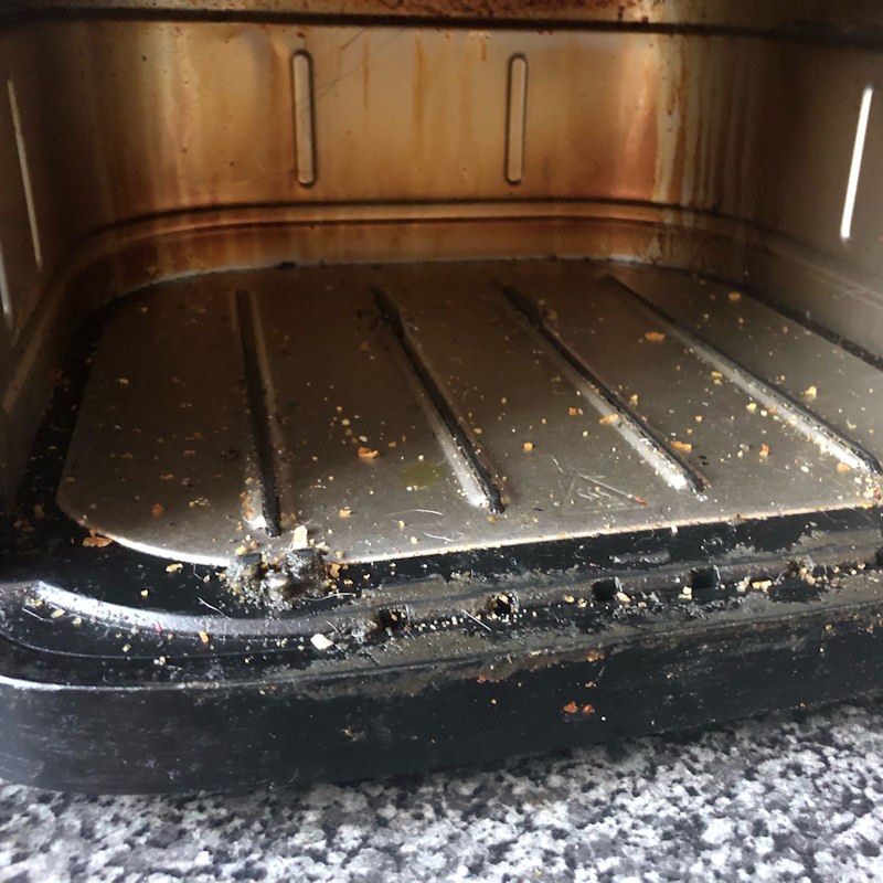 Poorly maintained internal air fryer basket, filled with crumbs and filth