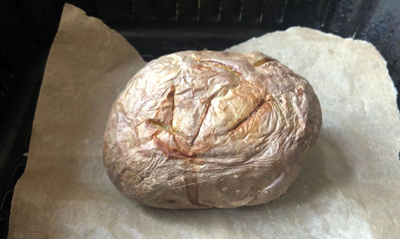 Air fried jacket potato positioned on parchment paper