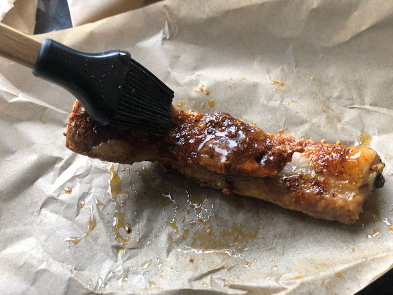 Brushing on watered-down honey barbeque sauce over rib slice with 
          silicone brush