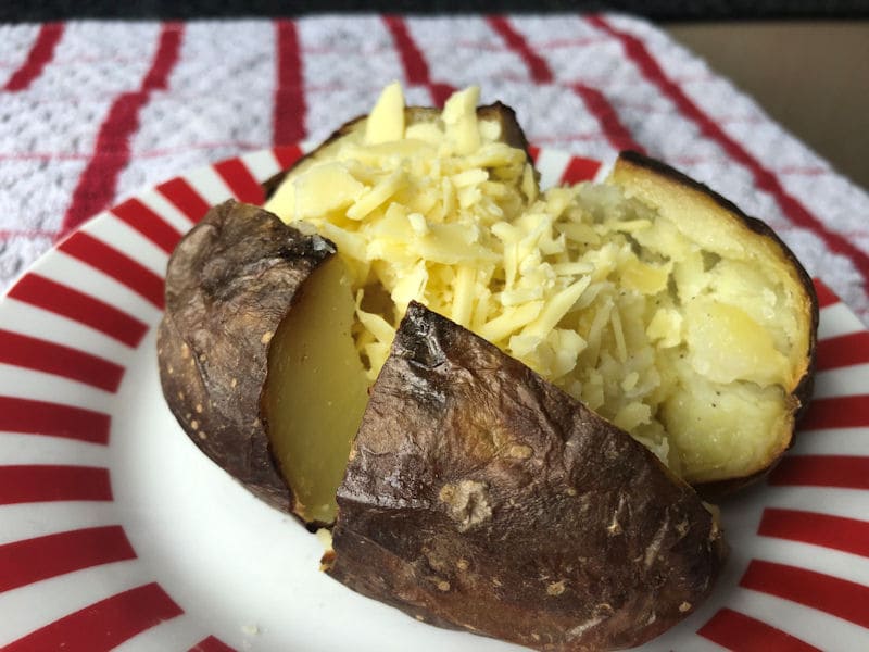 Reheated air fried jacket potato served with fresh grated cheese