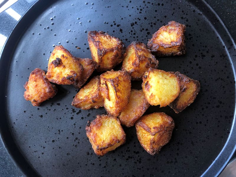 Serving of air fried roast potatoes on black plate