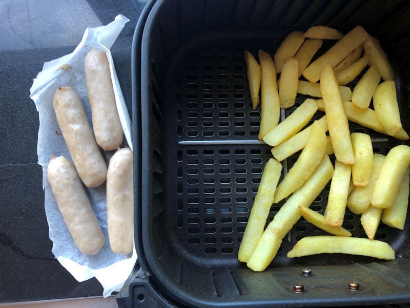 Sausages outside of air fryer, with chips in basket