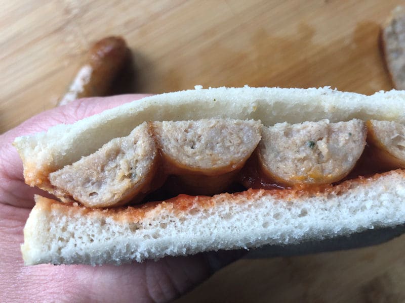 Me holding a white bread sausage butty with tomato ketchup