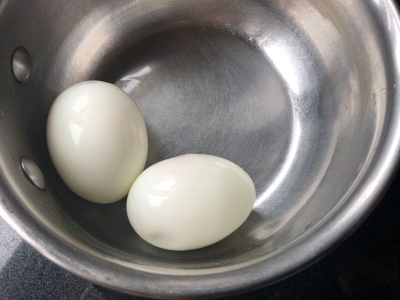 Peeled boiled eggs in small empty saucepan