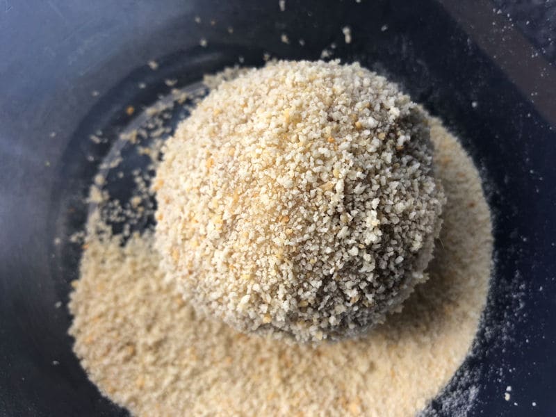 Raw Scotch Egg covered in breadcrumbs inside plastic bowl