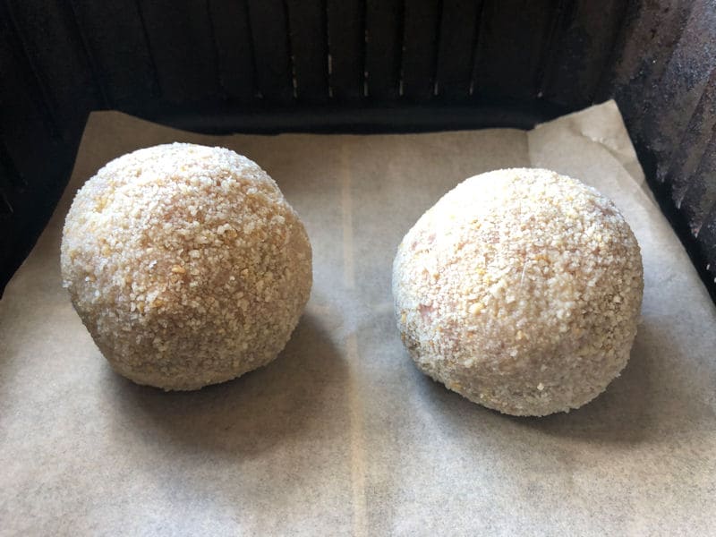 Perfectly formed round raw Scotch Eggs positioned on lining