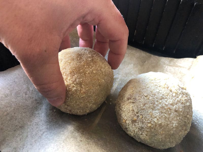 Grabbing partially cooked Scotch Egg by hand to turn over