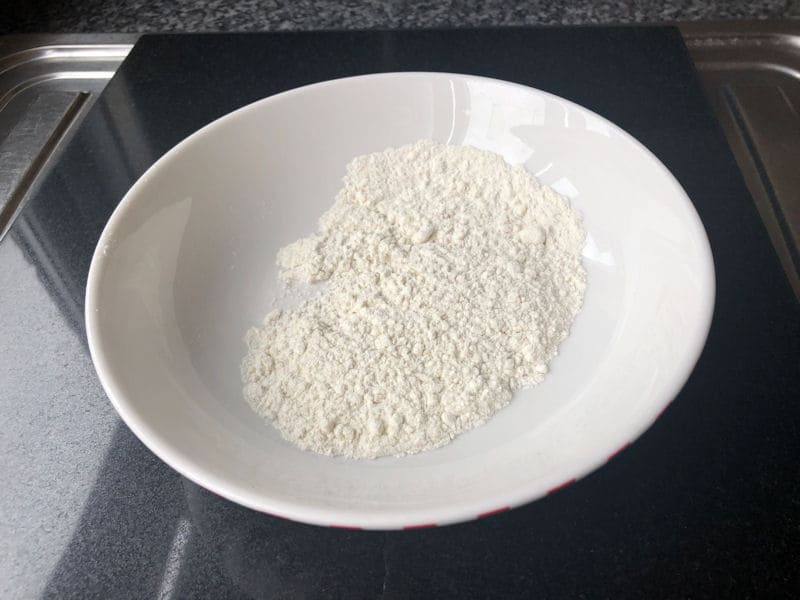 Flour in ceramic cereal bowl on chopping board