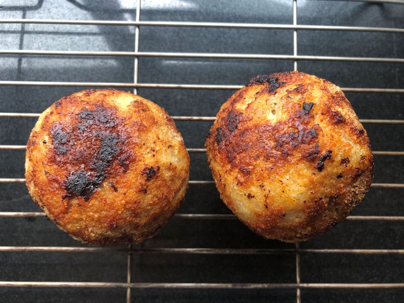 Fully cooked air fried Scotch Eggs cooling on metal rack