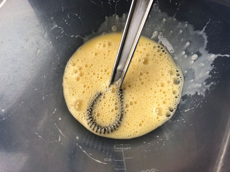 Beaten egg in plastic bowl with whisk