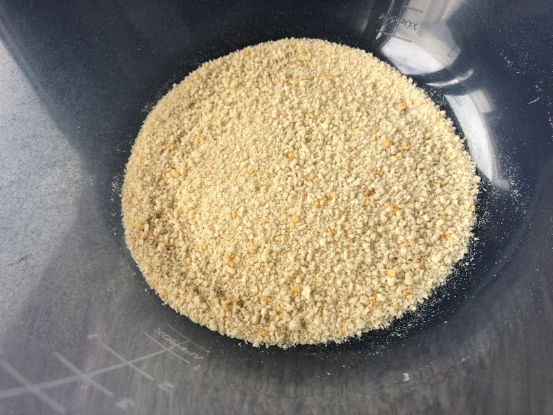 White breadcrumbs spread evenly in plastic bowl