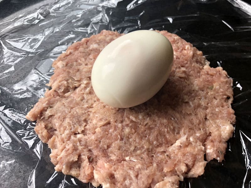 Hard boiled egg centred on sausage patty