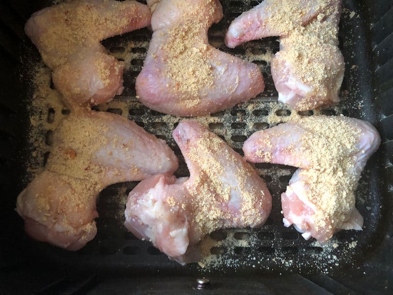 Chicken wings covered in seasoning inside air fryer