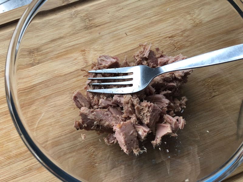 Can of tuna decanted in glass bowl, fork positioned on top