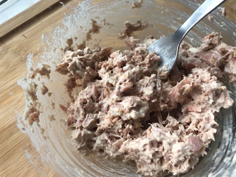 Combing tuna and mayo mix with fork in glass dish