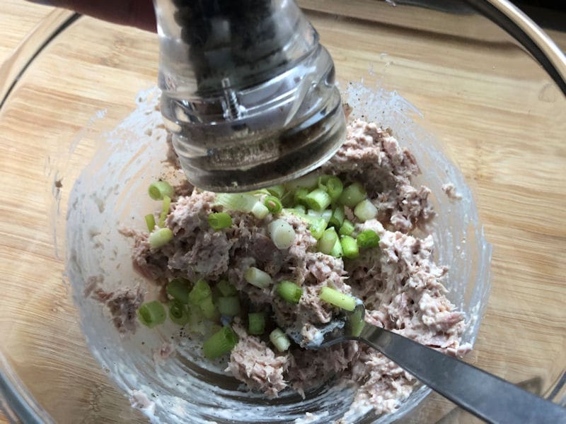 Seasoning tuna melt spread in glass dish with pepper grinder in sight