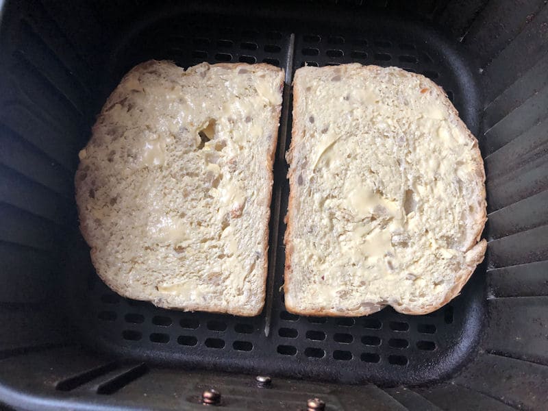 Buttered bread slices positioned side by side in air fryer