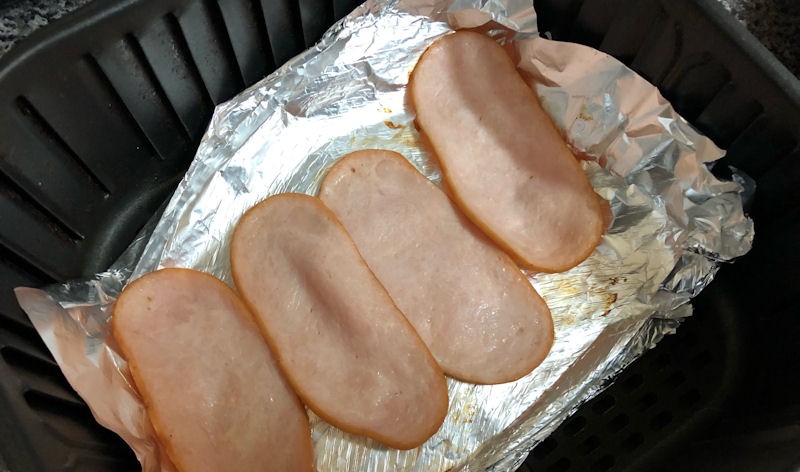 Four turkey bacon rashers sitting on foil in air fryer basket